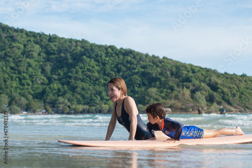 Mother teaches son the basics of surfing, surfing lessons on the beach, lifestyle activities, water sports