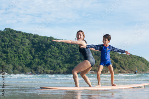 Mother teaches son the basics of surfing, surfing lessons on the beach, lifestyle activities, water sports