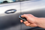Man closes his car door with the control remote key. Car remote control by smart key.