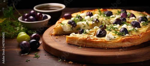 Rustic wooden table displaying a Greek tart topped with feta cheese and olives