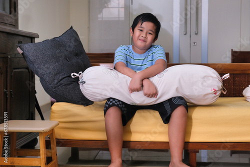 Chubby little Asian boy sitting alone after getting up from his sleep photo