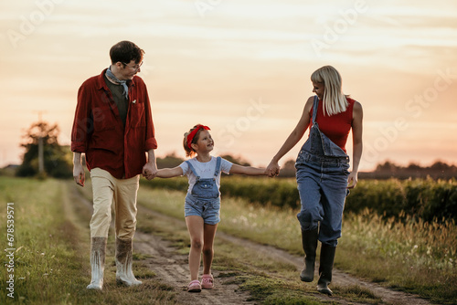 Father, mother, and their daughter enjoy the outdoors at sunset.