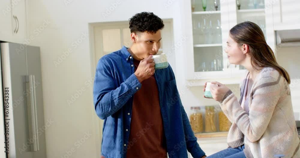 Happy diverse couple talking and drinking coffee in kitchen at home, in slow motion Happy diverse couple talking and drinking coffee in kitchen at home, in slow motion