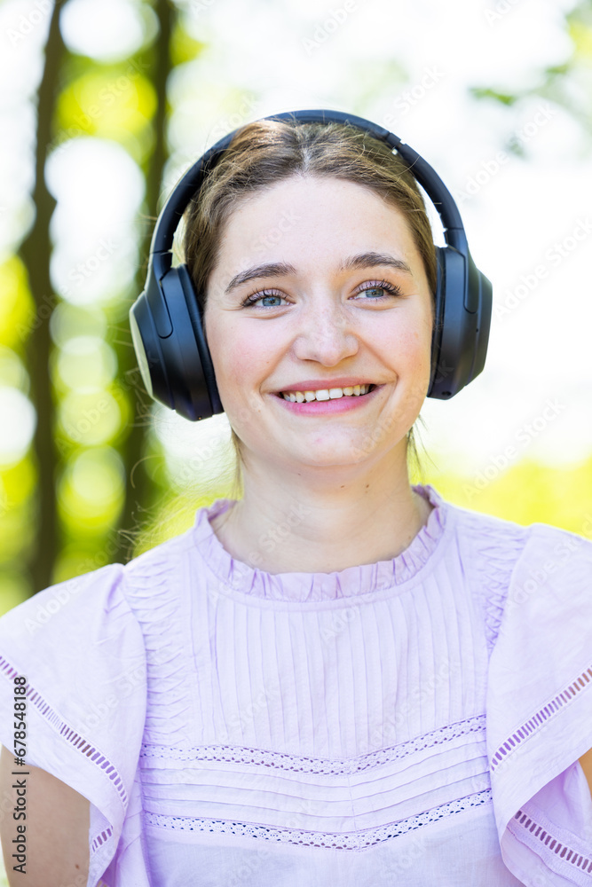 Captured in a close-up, a woman immerses herself in music through her headphones, a symbol of freedom and happiness in an outdoor setting. This serene green backdrop enhances the experience, perfect Captured in a close-up, a woman immerses herself in music through her headphones, a symbol of freedom and happiness in an outdoor setting. This serene green backdrop enhances the experience, perfect