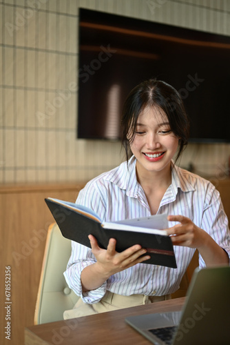 Portrait of successful young businesswoman checking working schedule plan at desk