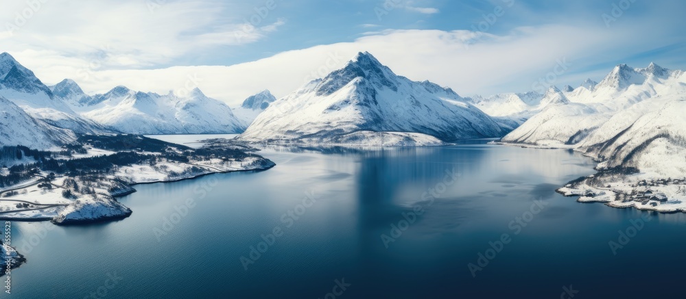 A wide lake nestled amidst snow capped mountains seen from above