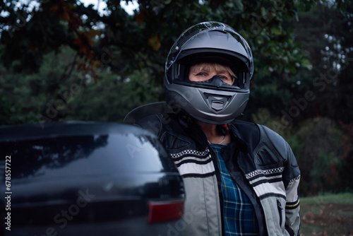 Motorcycle tourism. Unrecognizable woman in black closed motorcycle helmet next to her motorcycle. Hobby motorcycle tourism. Healthy lifestyle. Excellent physical shape. Tourism and travel. © Евгения Рубцова