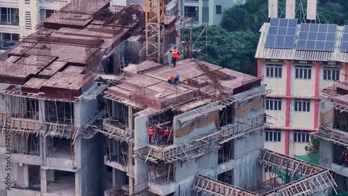 Construction workers working at roof top of an under construction building in Mumbai, India. Aerial shot if Indian construction workers fixing slabs on rooftop.