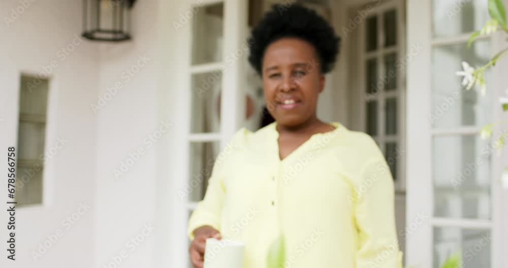 Happy african american senior woman walking with cup smiling outside house, slow motion Happy african american senior woman walking with cup smiling outside house, slow motion