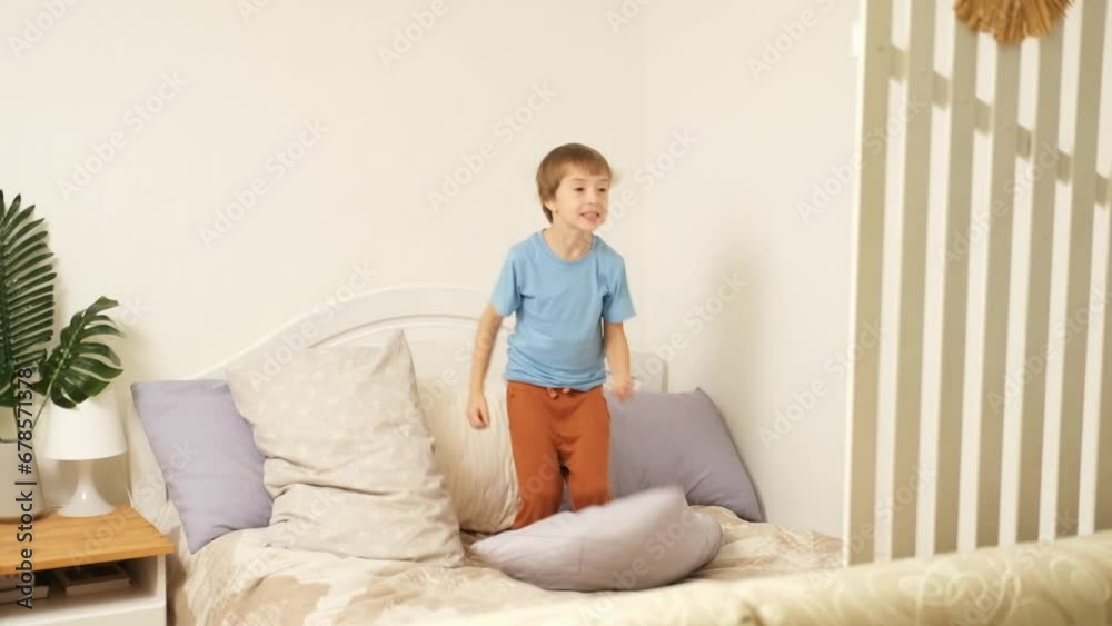 cheerful kid, young boy in pajamas having fun, dancing and jumping on the bed at home on sunny day. cheerful kid, young boy in pajamas having fun, dancing and jumping on the bed at home on sunny day.