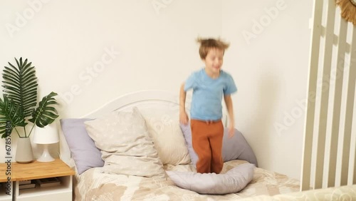 Funny adorable happy kid boy jump and dance on bed in the morning. Happy holidays and new day concept.