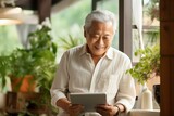家でタブレットを見る笑顔の日本人おじいさん（デジタル端末・ガジェット・iPad）