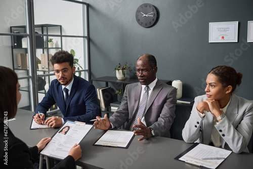 Fotografija Group of specialists asking questions to applicant during interview for getting