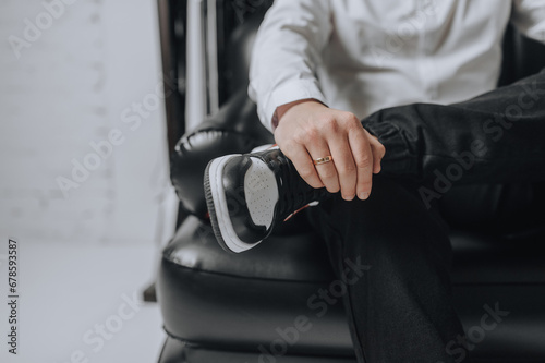 Confident man, businessman sitting on a leather chair in the office. Photo of a hand with a gold ring on the groom's finger.