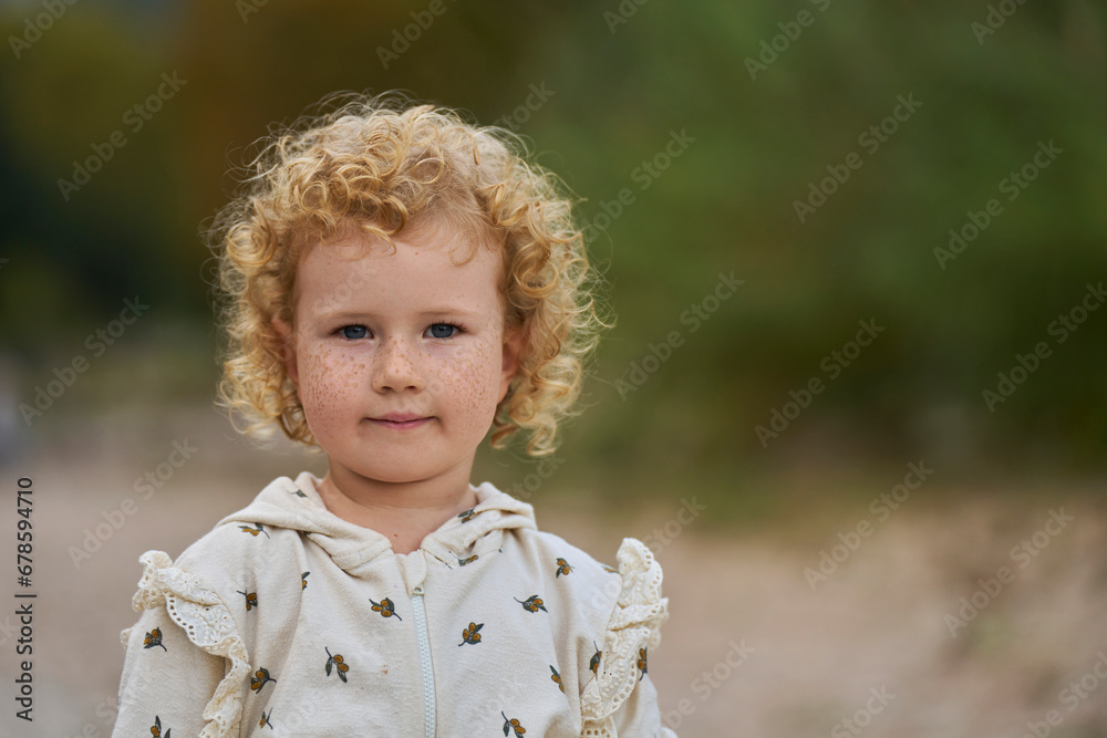 Smiling cute blond girl with curly hair and freckles on face Smiling cute blond girl with curly hair and freckles on face