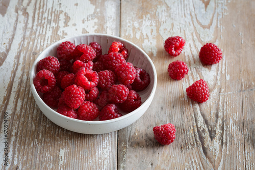 Bowl of fresh raspberries on wooden surface photo