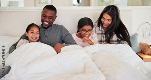Funny, family and kids in bedroom, tickle and play, bonding and happy together in the morning in home. Laughing children, mother and father in bed, smile and care of interracial people under blanket photo