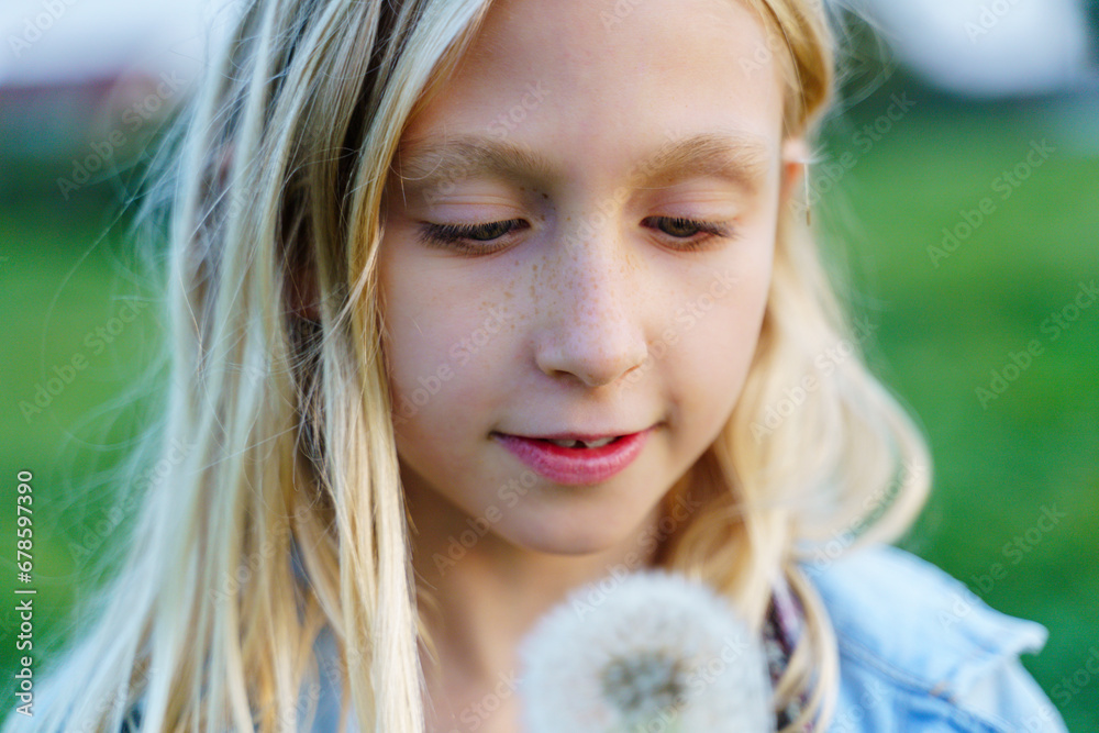 Blond smiling girl looking at dandelion Blond smiling girl looking at dandelion