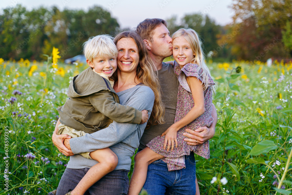 Happy parents carrying children in sunflower field