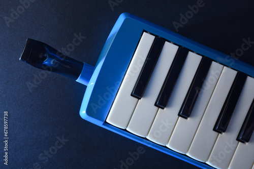 Melodica with mouthpiece to play directly on dark table photo