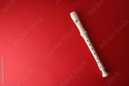 White plastic recorder on red gradient background photo