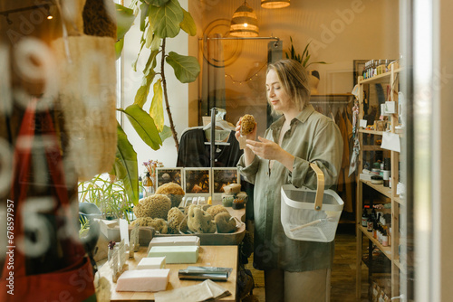 Woman choosing organic bath sponge and shopping in eco-shop photo