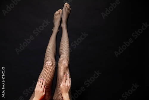 Beautiful slender female legs in pantyhose stockings on black background