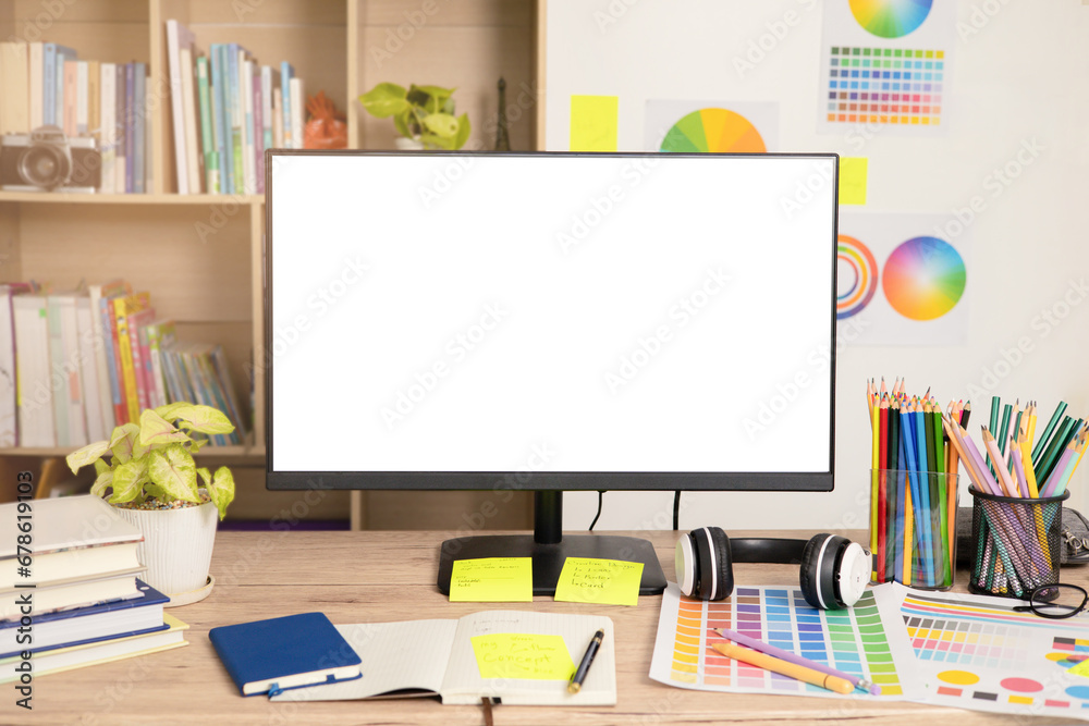 Graphic designer's workspace with a computer featuring a white screen and creative tools on the table