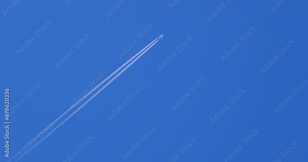 Airplane flying on deep blue sky with chemical direction trails, view from a distance Airplane flying on deep blue sky with chemical direction trails, view from a distance