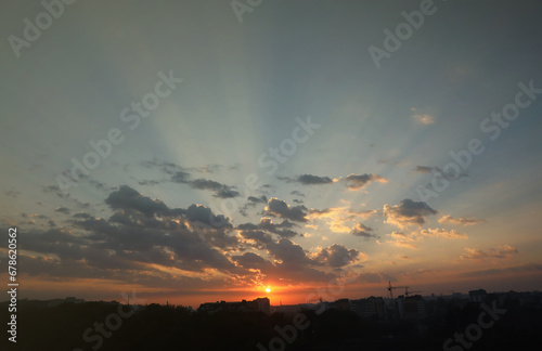 Beautiful sunrise with warm orange sunlight and beams through cloudy blue sky