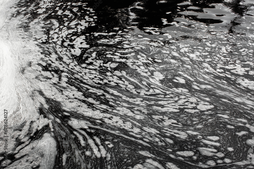Fototapeta premium Black waste water with white foam on water surface environmental pollution of nature from effluent factory.