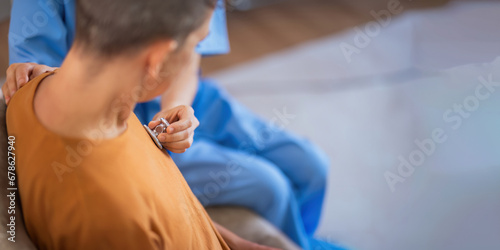 Therapist holding stethoscope listening old patient during homecare visit. Caregiver or doctor checking heartbeat examining elderly retired woman at home. Senior heart disease, cardiology concept photo