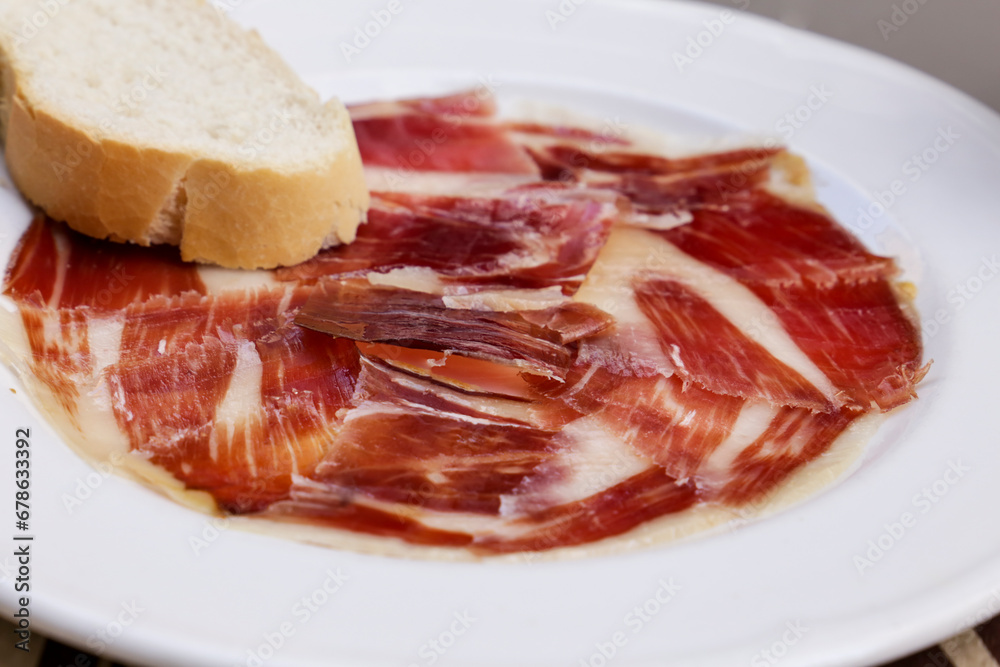 Tasty Iberico bellota ham plate with a slice of bread in a bar Tasty Iberico bellota ham plate with a slice of bread in a bar