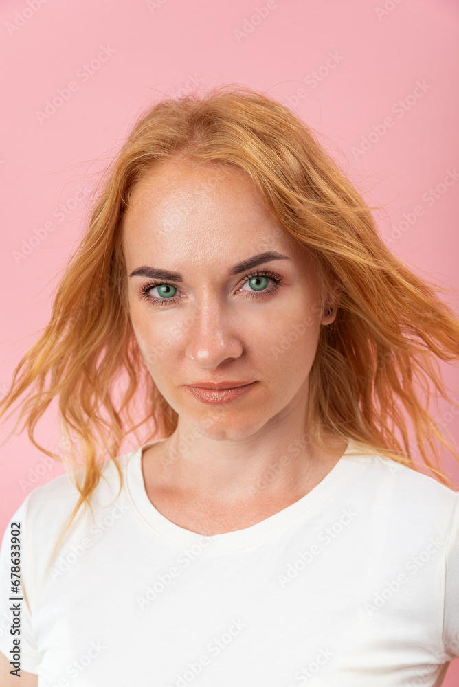 Portrait of attractive green eyed woman with red hair. Confident woman looking into the frame. Pink background, vertical frame Portrait of attractive green eyed woman with red hair. Confident woman looking into the frame. Pink background, vertical frame