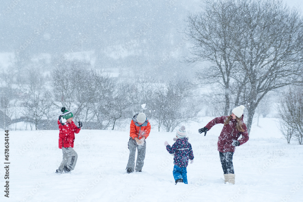 Children play snowballs outside during snowfall. Winter holidays. Games in winter outdoors. Children play snowballs outside during snowfall. Winter holidays. Games in winter outdoors.
