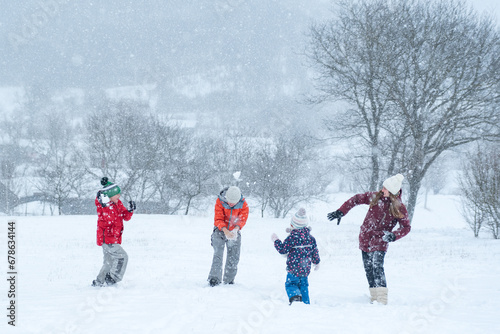 Children play snowballs outside during snowfall. Winter holidays. Games in winter outdoors.