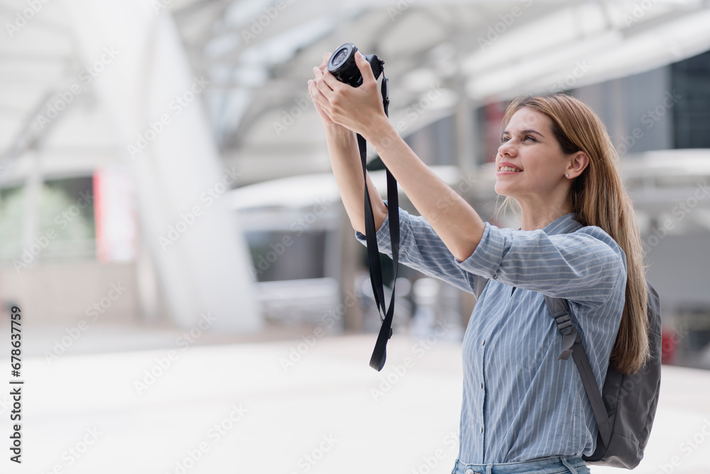 Woman photographer with big backpack taking photo. Travel and hobby concept. Woman Taking Picture Outdoors. Female photographer smiling cheerfully. Creative female freelancer working on a new project.