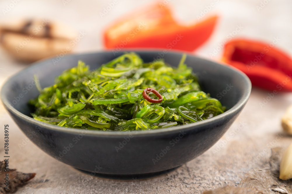 Chuka seaweed salad in blue ceramic bowl on brown concrete. Side view, selective focus Chuka seaweed salad in blue ceramic bowl on brown concrete. Side view, selective focus