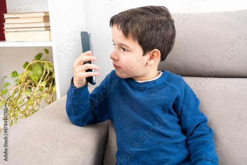 Принти на полотні Boy suffering from eyestrain trying to message on a smart phone in the living ro