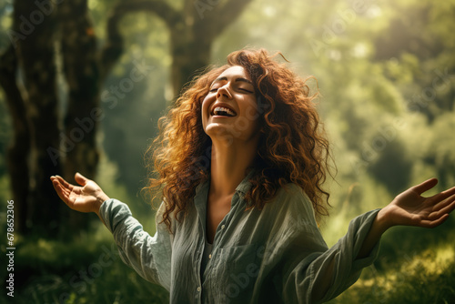 Happy woman with opened arms enjoying the green nature woods forest around her. Concept of healthy natural lifestyle.