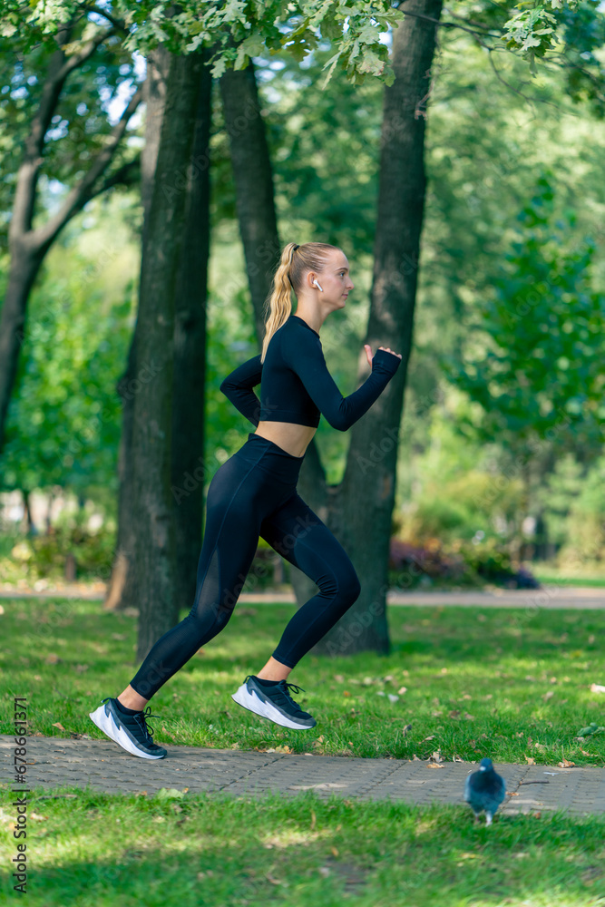 A young girl in sportswear and headphones runs in park in the morning to maintain physical fitness