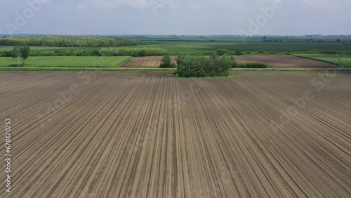 Aerial shot of red car with roof carrier driving along the road through cultivated landscape in summer, drone pov photo
