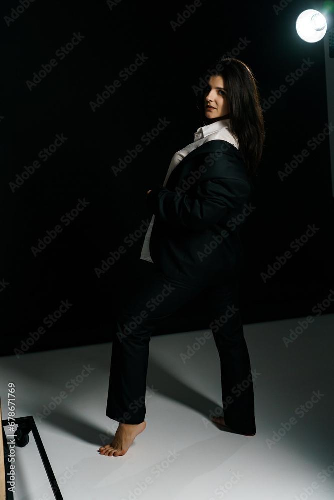 Stylish girl posing in a black suit and white shirt in a professional photo studio. Fashion shooting concept Stylish girl posing in a black suit and white shirt in a professional photo studio. Fashion shooting concept