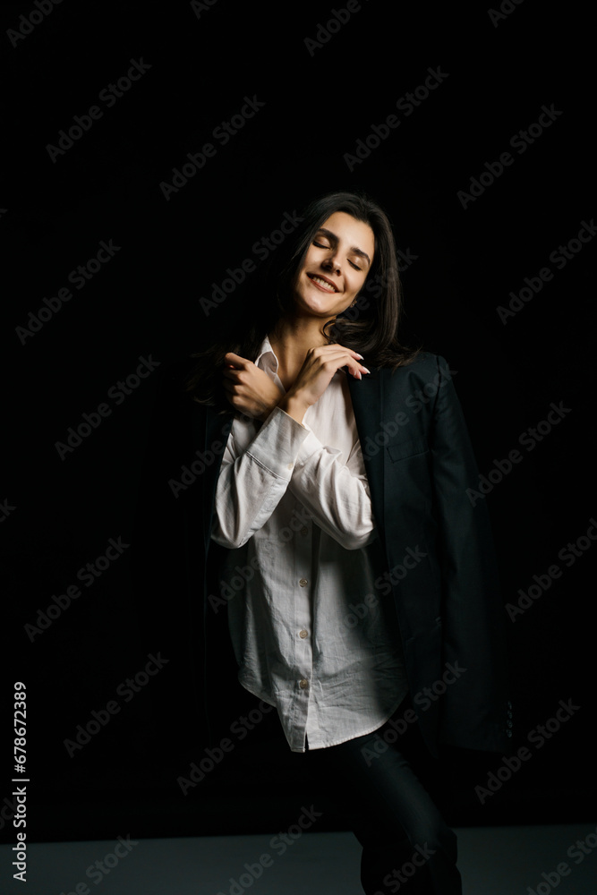 Stylish girl posing in a black suit and white shirt in a professional photo studio. Fashion shooting concept Stylish girl posing in a black suit and white shirt in a professional photo studio. Fashion shooting concept
