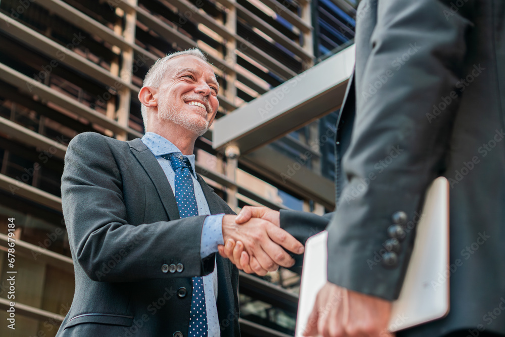 Two business men shaking hands for strike a deal. White collar workers smiling and having a collaboration. Businesspeople greeting at workplace. Corporate coworkers or partners in the workspace. Two business men shaking hands for strike a deal. White collar workers smiling and having a collaboration. Businesspeople greeting at workplace. Corporate coworkers or partners in the workspace.