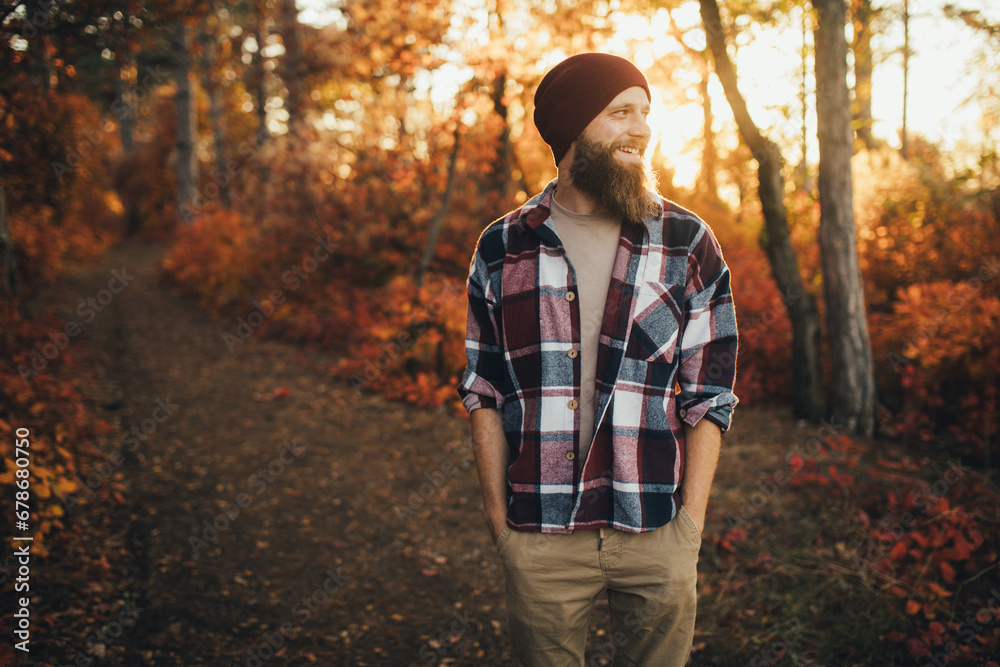 Happy young traveler with a beard wearing casual clothing walking in a forest. Happy young traveler with a beard wearing casual clothing walking in a forest.