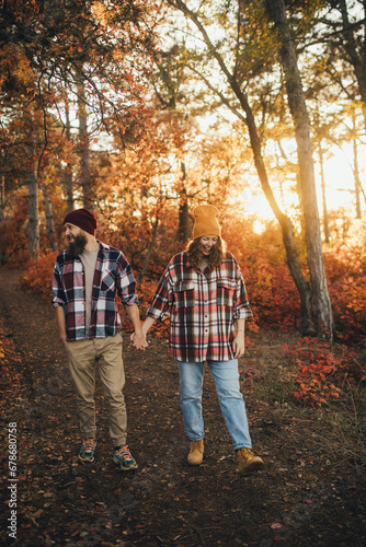 Happy couple wearing casual clothes walking together in an autumn forest.
