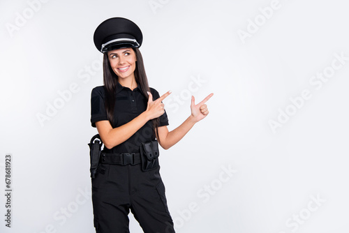 Photo of pretty charming young police lady wear black uniform cap pointing looking empty space isolated white color background photo