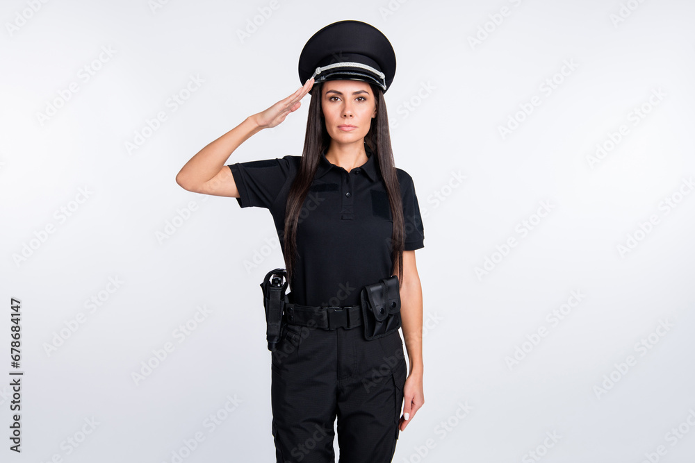 Photo of serious charming young policewoman dressed black clothes saluting arm headwear isolated white color background Photo of serious charming young policewoman dressed black clothes saluting arm headwear isolated white color background