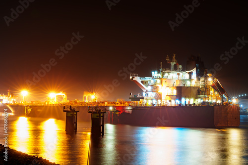 Majestic view of the Rotterdam port at night, shrouded in mist with the city lights illuminating the surroundings, creating a captivating and atmospheric scene.